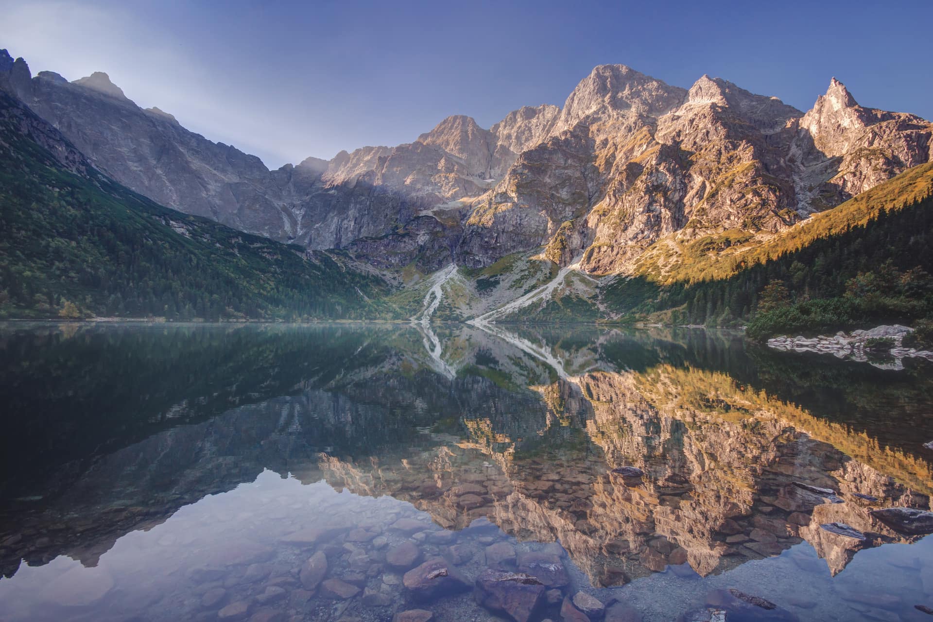 Morning light on the peaks above Morskie Oko lake in the Tatra Mountains, reflected in still water